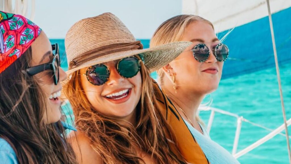 Women enjoying a private sailing charter on calm waters, relaxing on deck with scenic ocean views.