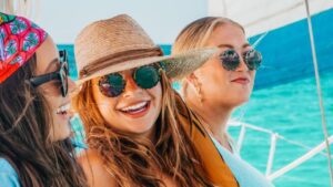 Women enjoying a private sailing charter on calm waters, relaxing on deck with scenic ocean views.