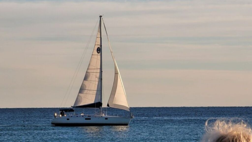 Sailboat on calm open water at sunset.