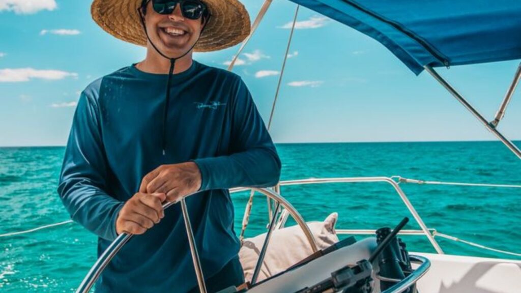 Man enjoying a private sailing charter while steering a sailboat in Destin, Florida.